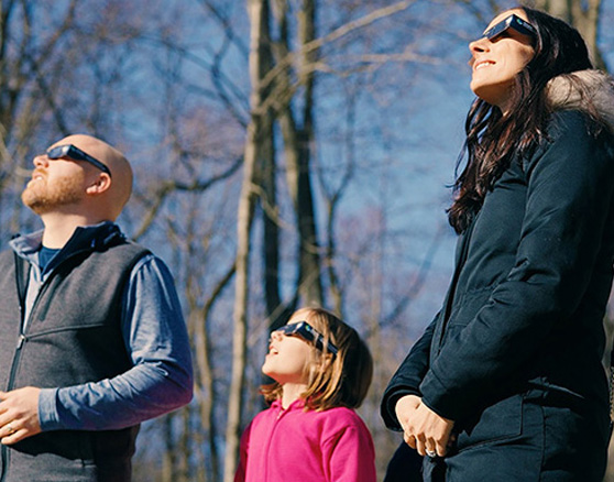 a family wearing eclipse glasses while watching a solar eclipse